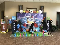 some people are standing in front of a game on the field display with footballs