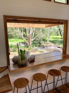 there are four stools in front of the window that looks out onto the woods