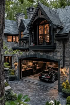 a car is parked in front of a large stone building with two story windows and dark shingles