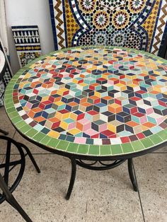 a table that is sitting on top of a tile floor with colorful tiles around it