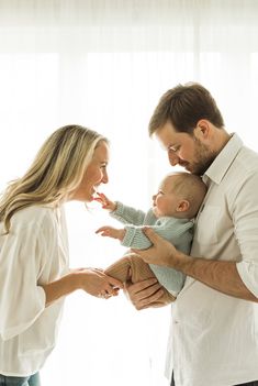 a man and woman holding a baby in their arms