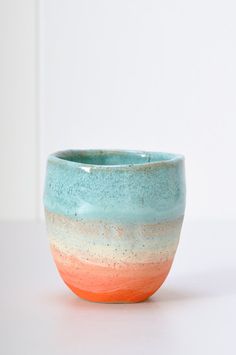 a blue and orange bowl sitting on top of a white table next to a wall