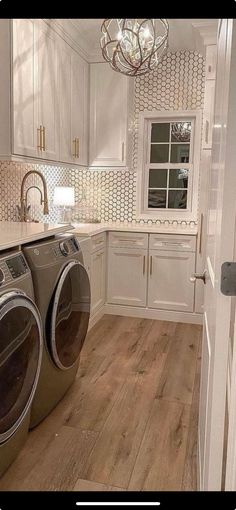 a washer and dryer in a white kitchen with wood flooring on the walls