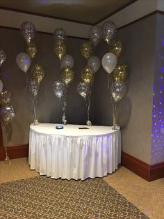 a table topped with lots of balloons next to a wall