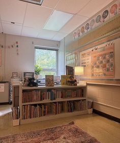 a room with bookshelves and a rug in front of a window that has pictures on the wall