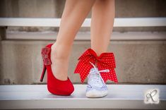 a woman's feet wearing red and white high heels with bows on the toes