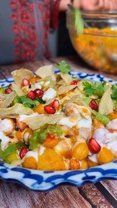 a blue and white plate filled with food on top of a wooden table next to a bowl