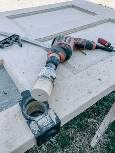 a drill is laying on the ground next to a door frame and tools are lying around it