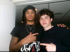 two young men standing next to each other in front of a white wall and ceiling