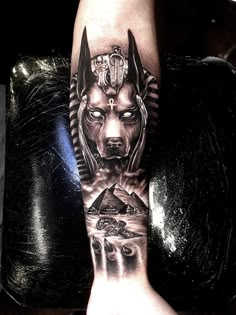 a man's arm with an egyptian mask and pyramids on the cover up