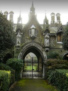 an old building with a gate and some bushes