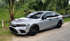 a silver car parked on the side of a road next to some trees and grass