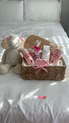 a teddy bear sitting on top of a bed next to a basket filled with items