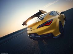 a yellow sports car with a surfboard on the roof is driving down the road