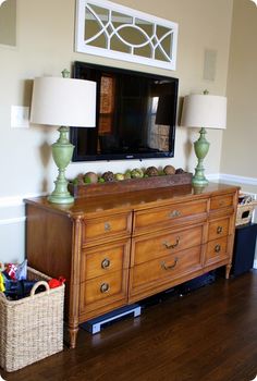 a living room with a large tv mounted on the wall and two lamps in front of it