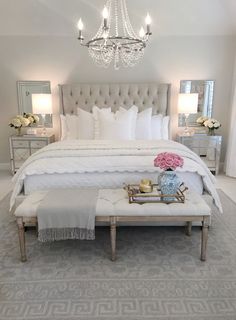 a bedroom with a large bed, chandelier and two tables in front of it