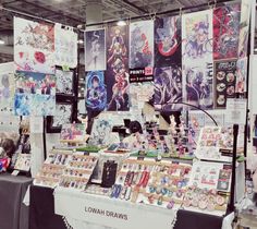 the booth is full of comic books and merchandise for sale at an art fair or convention