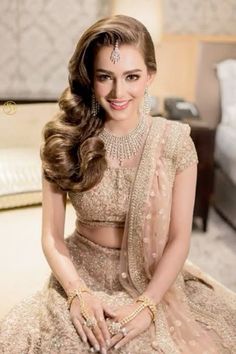 a woman sitting on top of a bed wearing a dress and jewelry in her hand