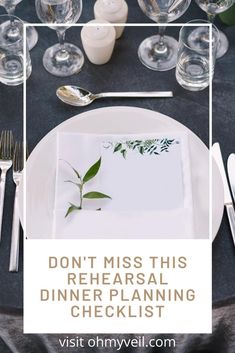 a white plate topped with a green plant on top of a black table cloth next to silverware