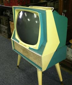 an old fashioned television sitting on top of a wooden stand in a room filled with other items