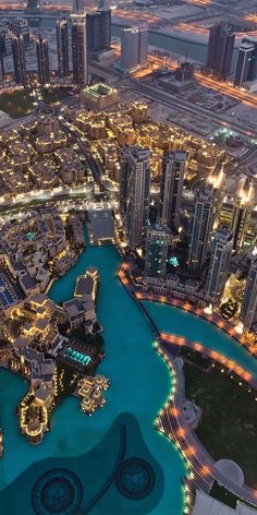 an aerial view of a city at night with lights on the buildings and water in the foreground