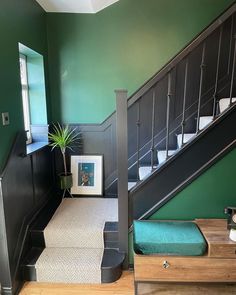 the stairs in this house are painted green and have black handrails that lead up to the second floor