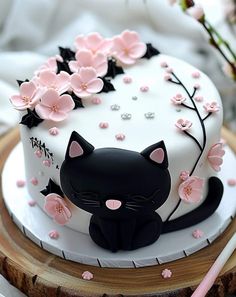 a white cake decorated with black cat and pink flowers