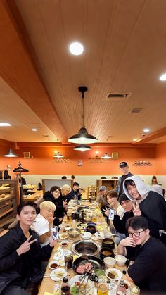 a group of people sitting at a long table with food and drinks in front of them