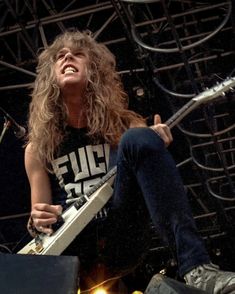 a woman sitting on top of a stage with a guitar in her hand and smiling