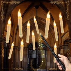 a person holding a wand in front of an arch with lit candles hanging from it