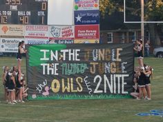 the cheerleaders are standing in front of a large banner that reads in the name of the football team