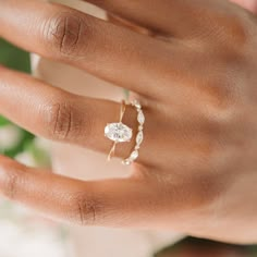 a woman's hand holding a ring with a diamond in it and pearls on the band