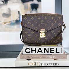 a brown purse sitting on top of a stack of books