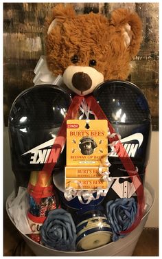 a brown teddy bear sitting in a bucket filled with assorted items