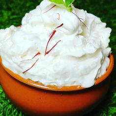 a bowl filled with whipped cream on top of green grass