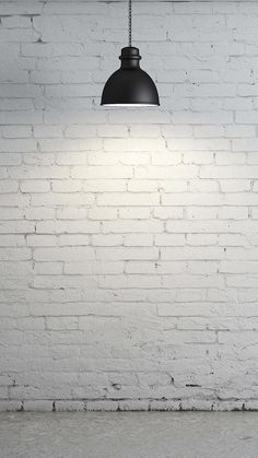 a white brick wall with a black light hanging from it's side and an empty floor below