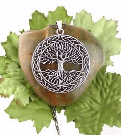 a tree of life pendant is shown on a leafy branch with leaves around it