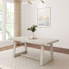 a white table with a vase on top of it in front of a large window