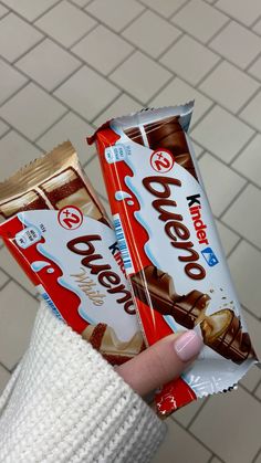 a person holding two bars of chocolate in their hand on a tiled floored area