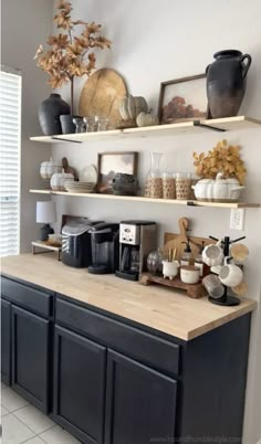 a kitchen counter with coffee maker, cups and other items on shelves above the counter