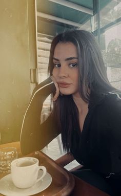 a woman sitting at a table with a coffee cup