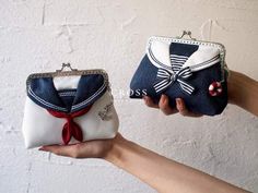 two purses are being held by someone's hand, one has a bow on it