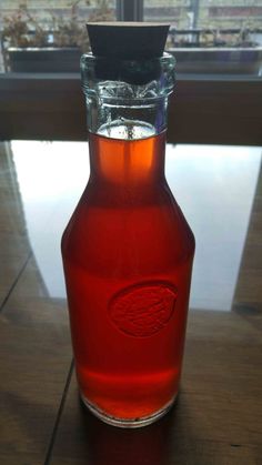 a glass bottle filled with liquid sitting on top of a wooden table