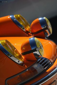 an orange sports car with two mirrors on it's headlamps and the hood