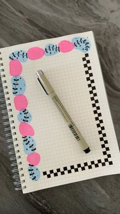 a pen sitting on top of a notepad next to a checkered paper border