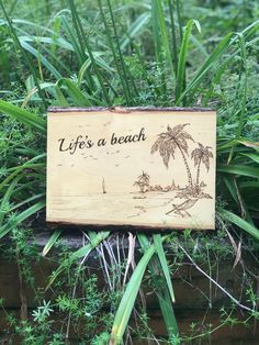 a wooden sign that says life's a beach in front of some green plants