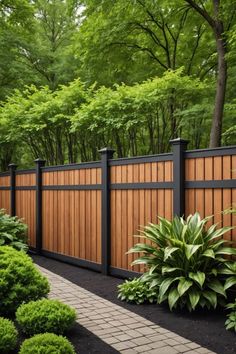 a wooden fence surrounded by lush green trees and shrubbery on either side of it