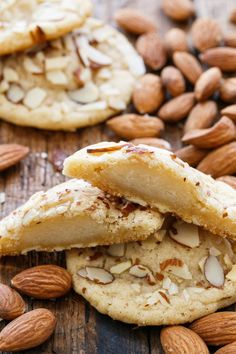 almond cookies are stacked on top of each other with one cookie cut in half and the rest broken