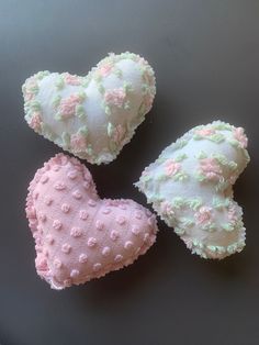 three heart shaped pillows sitting on top of a table