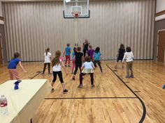 a group of young people standing on top of a wooden floor next to a basketball court